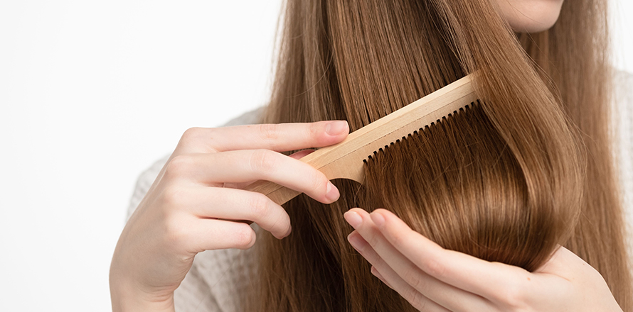 šampony - žena si pročesává hnědé vlasy