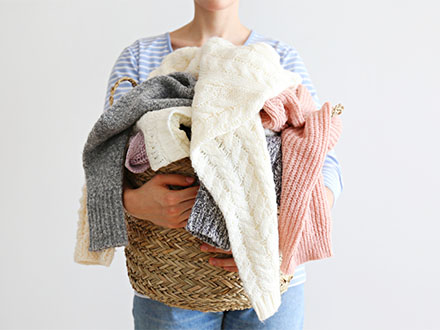 žena s hromadou svetrů na praní 