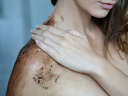 jak připravit tělo na opalování - žena aplikuje peeling na ramena